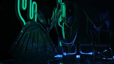 Siyah arka planda yeşil ışıkla işaretlenmiş bardaklar ve çekimler. Alçak tuş.