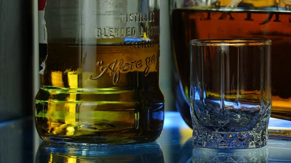 Cam yüzeyde bir bardak ve bir şişe viski..