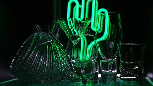 Siyah arka planda yeşil ışıkla işaretlenmiş bardaklar ve çekimler. Alçak tuş.