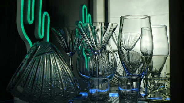 Siyah arka planda yeşil ışıkla işaretlenmiş bardaklar ve çekimler. Alçak tuş.