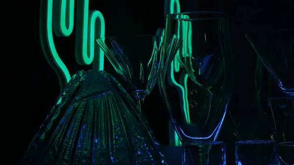 Siyah arka planda yeşil ışıkla işaretlenmiş bardaklar ve çekimler. Alçak tuş.