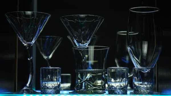 Siyah arka planda yeşil ışıkla işaretlenmiş bardaklar ve çekimler. Alçak tuş.