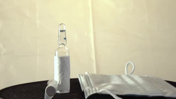 Σύριγγα, ιατρική μάσκα και εμβόλιο στο μαύρο περιστρεφόμενο τραπέζι. — Αρχείο Βίντεο