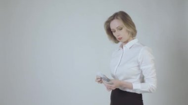 Sarışın güzel bir kadın gri arka planda para sayıyor.