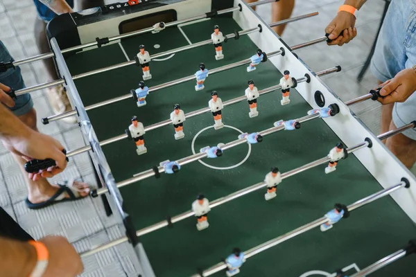 Çocuklar yukarıdan futbol maçı izliyorlar. beyaz ve mavi oyuncuları olan masa futbolu