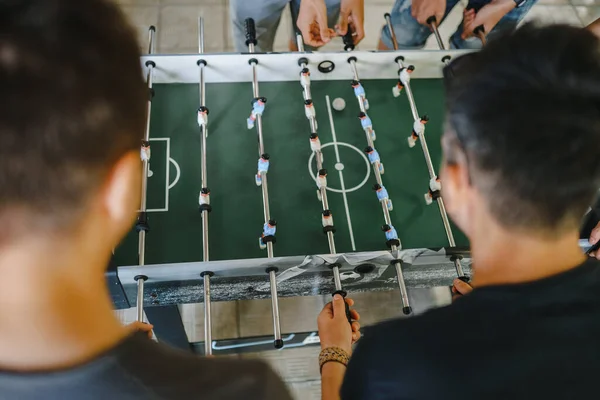 Çocuklar yukarıdan futbol maçı izliyorlar. beyaz ve mavi oyuncuları olan masa futbolu