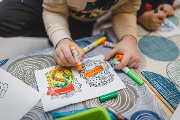 Cute little child is drawing with felt-tip pen in preschool. child paints print. drawing lesson in kindergarten