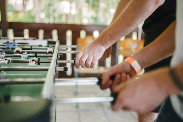 table football soccer with white and blue players. close-up to hands playing table football. guys are playing table football