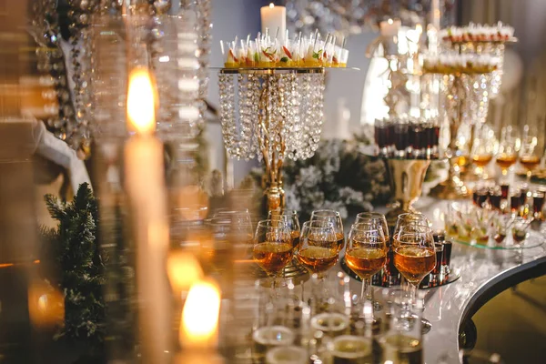 long luxury sumptuous decorated banquet table. high floating candles, crystal and gold ,champagne in glasses flute, appetizer and cold cuts