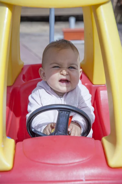 特写镜头的有趣的小女孩，驾驶玩具车 — 图库照片