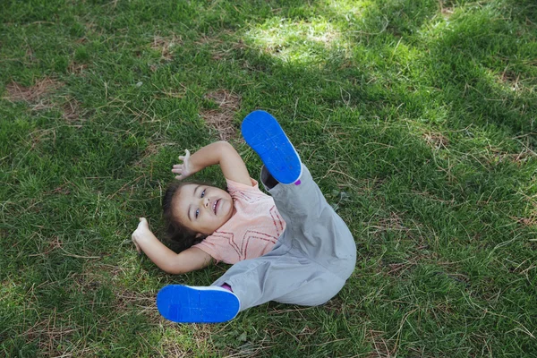 Little girl lying on lawn with legs up — Stock Photo, Image