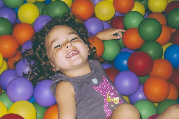 Playful girl lying in ball pit — Stock Photo, Image