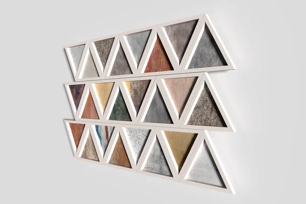 Pared con triángulos de diferentes materiales en marcos blancos —  Fotos de Stock
