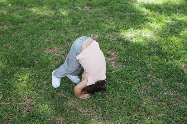 Menina fazendo salto mortal no gramado Imagens Royalty-Free