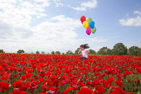 Zijaanzicht van meisje loopt langs veld met ballonnen — Stockfoto