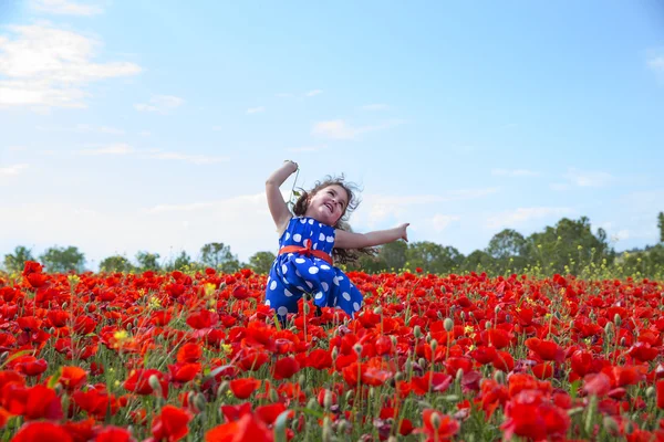 Pequena menina sorrindo pulando no campo de flores — Fotografia de Stock