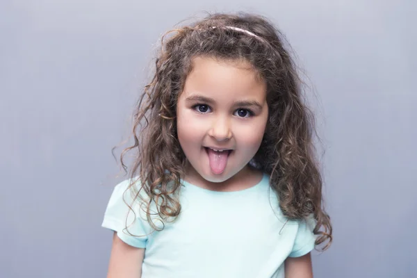 Porträtt av curly-haired girl sticker ut tungan — Stockfoto
