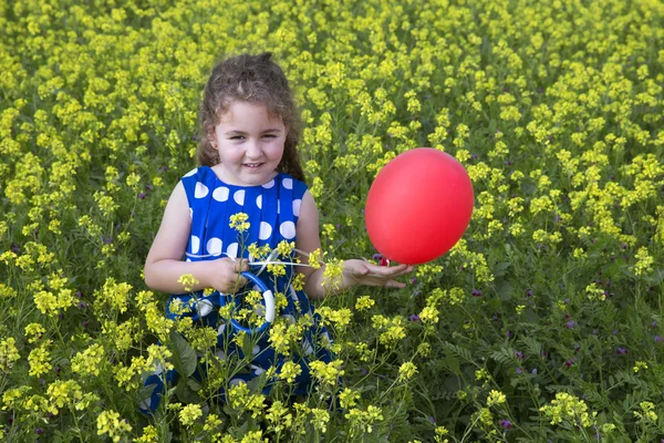 Usměvavá brunetka hraje s červeným balónkem v jasně žluté — Stock fotografie