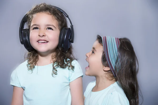 Uśmiechnięte dziewczyny, słuchanie muzyki w słuchawkach z siostrą krzyk — Zdjęcie stockowe
