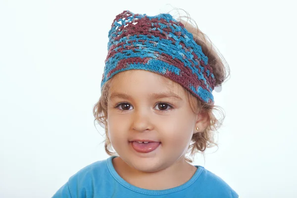 Schönes Kind in blauem Strickstirnband, das die Zunge herausstreckt — Stockfoto