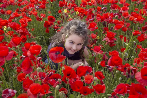 Schattig meisje glimlachend op camera op veld met poppy bloemen — Stockfoto