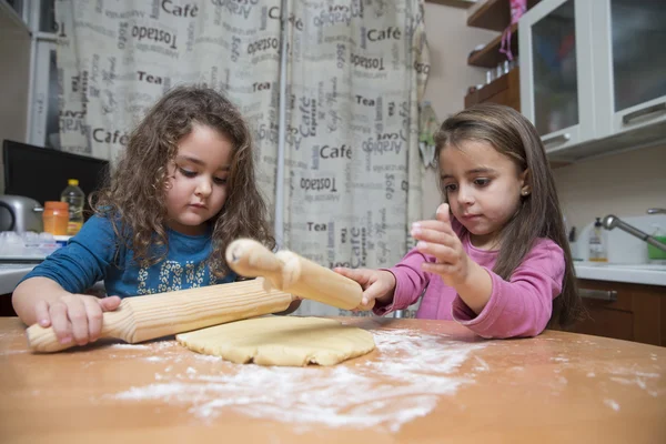 Zwei schöne Kinder kochen Teig mit Nudelholz in der heimischen Küche — Stockfoto