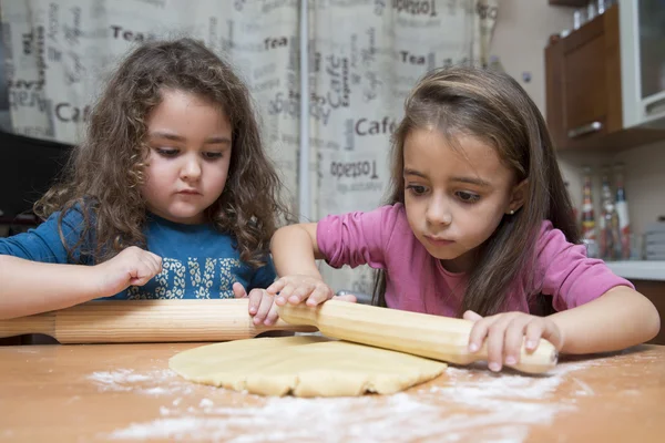 Duas crianças bonitas cozinhando massa com alfinetes rolantes na cozinha doméstica — Fotografia de Stock