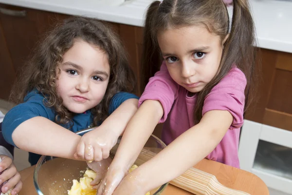 Zwei hübsche Mädchen, die Teig mit Händen mischen — Stockfoto