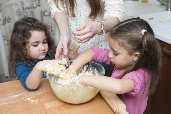 Zwei hübsche Mädchen und Mutter, die Teig mit den Händen mixen — Stockfoto