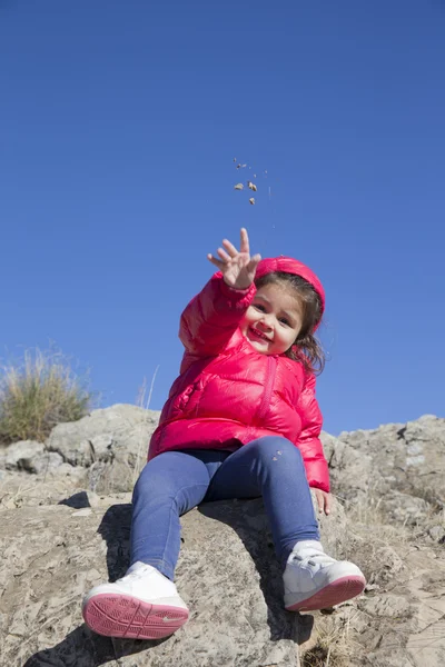 Bella bambina che lancia piccole pietre alla macchina fotografica — Foto Stock