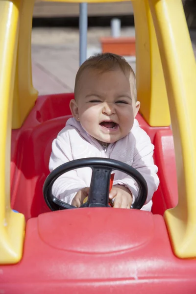 Close-up of funny little girl driving toy car — Stock Photo, Image