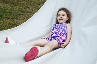 Küçük kız açık havada beyaz bez üzerinde yalan gülümseyen