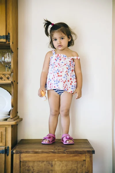 Bedårande liten tjej i klänning står på bordet — Stockfoto