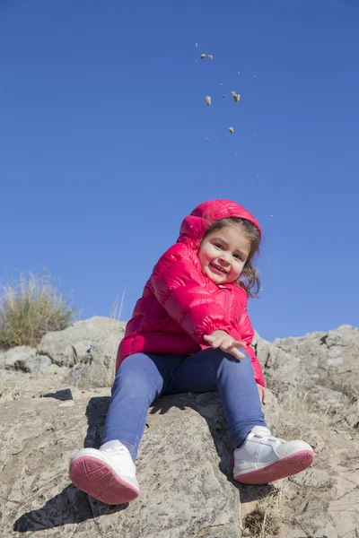 Lovely little girl throwing small stones to camera — Stock Photo, Image