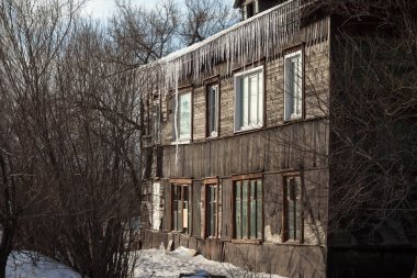 Eski bir evin çatısından aşağı asılı buz sarkıtları