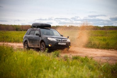 Nikolaevka, Rusya - 23 Haziran 2020: Kara Subaru Forester kirli orman yolunda ilerliyor ve çok fazla su sıçrıyor