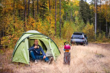 Sukpai, Rusya - 16 Eylül 2017: Sonbahar ormanlarında turist çadırında çay içen adam