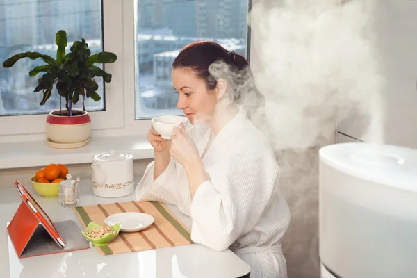 Mujer bebiendo té tableta de lectura en el humidificador — Foto de Stock