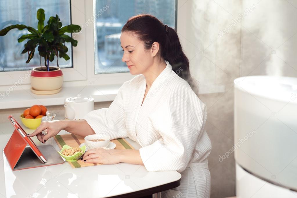 Woman sitting with tablet PC on the background of humidifier