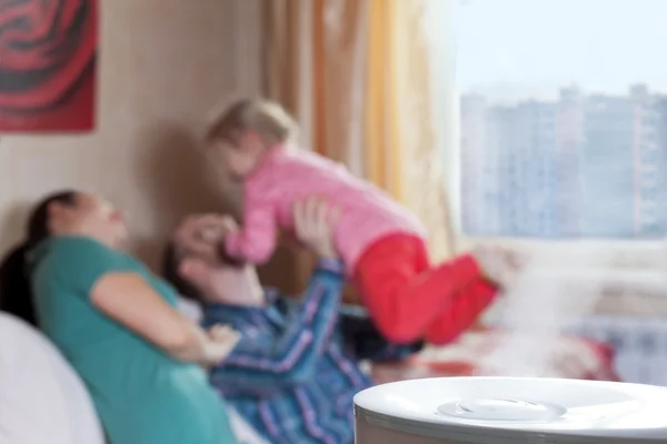 Föräldrarna spelar med deras dotter på bakgrund av humidif — Stockfoto