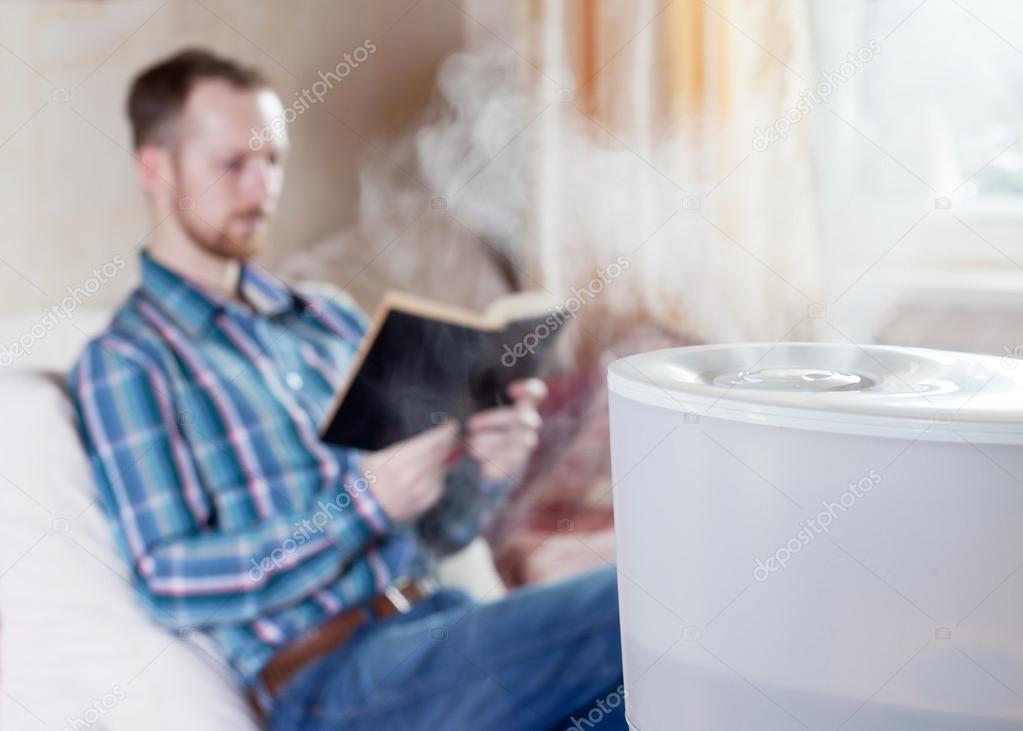 Man reading book on the background of humidifier