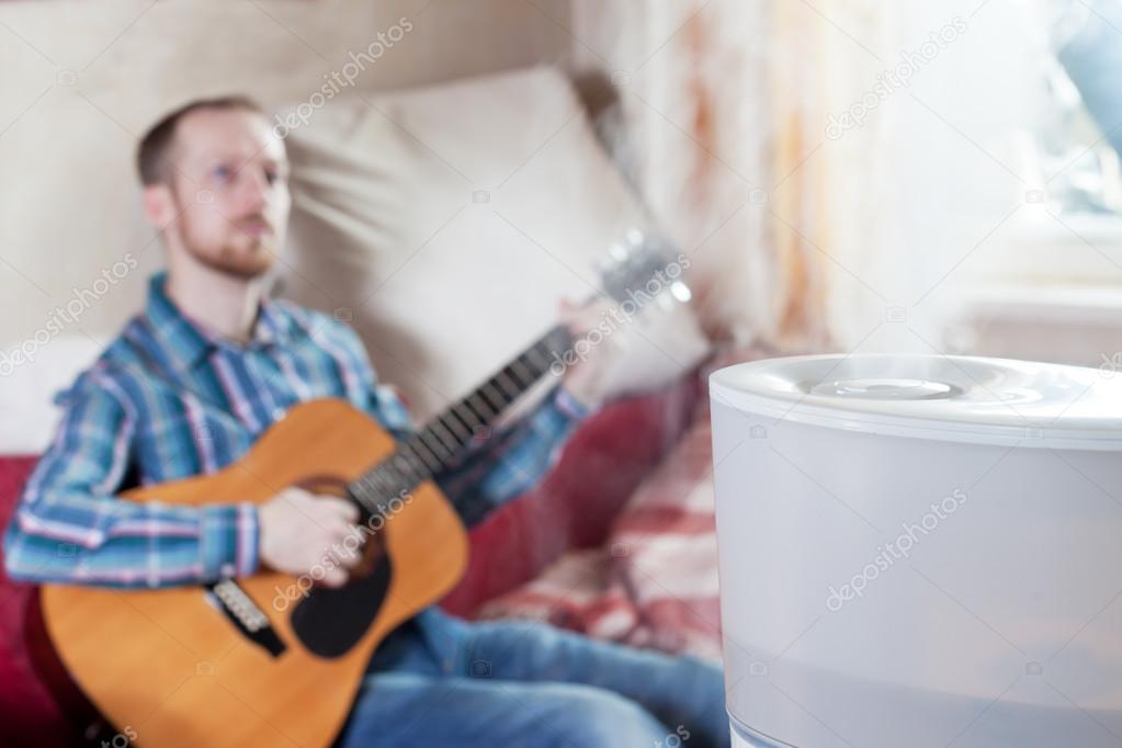 Man playing guitar on the background of humidifier