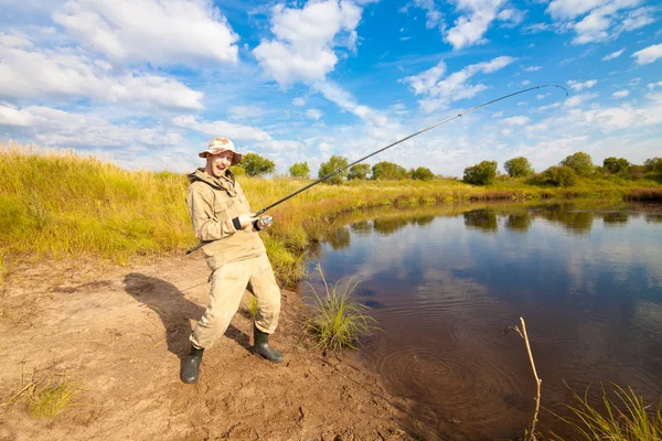 Fiskare med fisk-stav i handen fiske nära en damm — Stockfoto