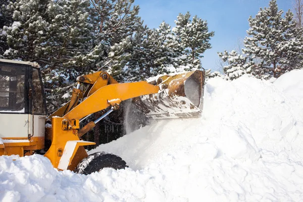 Carregador de rodas está limpando uma estrada de neve — Fotografia de Stock