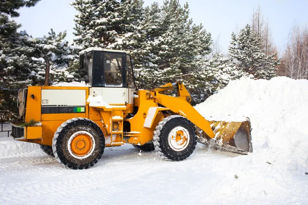 Carregador de rodas está limpando uma estrada de neve — Fotografia de Stock