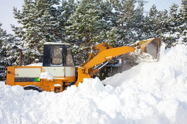 Carregador de rodas está limpando uma estrada de neve — Fotografia de Stock