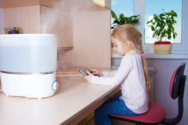 Niña con tableta pc sentado cerca del humidificador — Foto de Stock