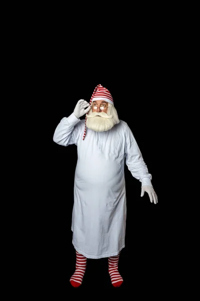 Pijamalı Noel Baba, gözlüklerinden uykulu gözlerle bakıyor. Siyah bir arkaplanda.