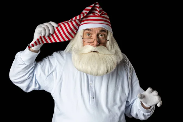 Gecelik ve gözlük takmış sakallı bir Noel Baba uyumak için gece içkisi tutar. Siyah bir arkaplanda.