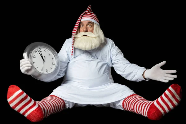 Gecelik ve gece içkisi giymiş Noel Baba yerde oturuyor ve Noel 'e neden geç kaldığını anlamıyor. Siyah bir arkaplanda.
